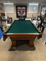 Full view of oak billiards table with green felt and leather fringe pockets