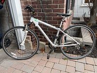 Full side view of silver Gary Fisher Tiburon bike leaning against brick