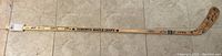 Full view of the signed Toronto Maple Leafs hockey stick laid on a tiled floor