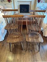 Front view of all four walnut Windsor chairs arranged in a row.