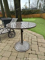Front view of table showing lattice top, pedestal base and umbrella hole in outdoor setting.