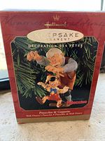 Front view of original red box showing Hallmark Keepsake Ornament featuring Geppetto and Pinocchio hanging on a Christmas tree branch, title and branding visible.