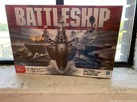 Front view of the sealed Battleship board game box showing battleships and aircraft artwork with large title.
