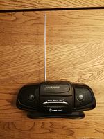 Front view of Lifelong Baby Boombox on wooden surface showing cassette player, speakers, antenna fully extended, and branding.