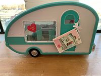Full view of Lori camper toy caravan in pastel teal and pink with note card showing figure set attached