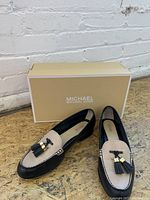 Michael Kors women's leather tassel loafers with beige and black color blocking displayed with original beige shoe box.