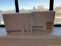 Two boxed Yummi brand tealight & votive holders, new in box, packaging visible.