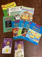 Top-down view of assorted educational books and workbooks for first grade including phonics library books and thematic storybooks