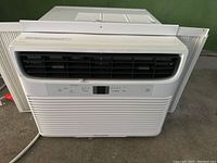 Front view of white Frigidaire window air conditioner showing control panel, adjustable vents, and power cord.