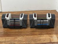 Front view of PowerBlock adjustable dumbbells showing weight plates and metal handles.