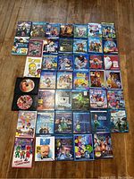 Photo of 45 family and kids movies in Blu-ray and DVD format, displayed on a wooden floor.