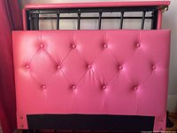 Close-up of pink tufted headboard upholstery with button details.