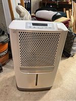 Full front view of white Frigidaire dehumidifier showing perforated air intake, water tank slot, and control panel at the top.