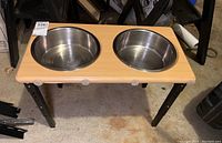 Front angle view of raised dog bowl set showing stainless steel bowls and wood base with metal legs