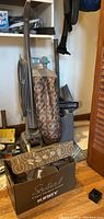 Kirby G10D upright vacuum with patterned fabric bag and electrical cord, standing with attachments nearby.