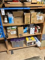 Various unopened and loose light bulbs stored on wooden shelves in boxes and blister packs