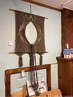 Full view of macrame wall art with hanging plant holder suspended below