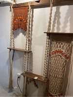 Front view of full macrame hanging shelves showing two wooden shelves with braided rope cords and bead details.
