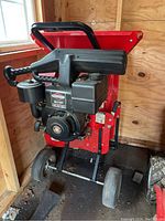 Front view of chipper shredder showing red steel hopper, black engine housing, and wheels