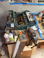Overhead view of open green cantilever toolbox with tools and bench vise on wooden table