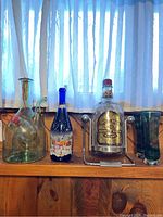 Wide shot of lot items including wine chiller, painted bottle, Chivas Regal bottle and rack, two glass vases.