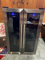 Front view of the Nutrichef wine cooler fridge showing dual black glass doors with stainless steel frames and handles, digital temperature readouts showing 41°F and 55°F on respective doors.