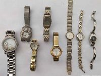 A group of eight vintage wristwatches with varying designs and metal bands, arranged in a row.