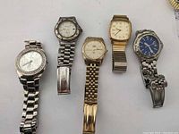 Overview of five vintage watches laid flat showing face and metal bands