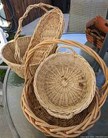 Four woven baskets on a glass outdoor table as a set. Various shapes and sizes clearly visible.