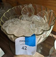 Photo of glass punch bowl filled with the matching cups inside, showing scalloped edges and clear glass design.