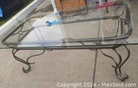 Full view of the rectangular glass top coffee table with wrought iron base, showing the curved legs and glass surface.