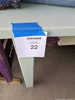 Close-up photo of the table corner showing the light green paint and minor paint blistering.