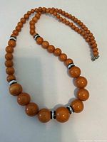 Full view of light brown beaded necklace showing bead sizes and detail of dividers and clasp.