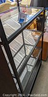 Front angled view of shelving unit showing glass shelves and metal frame.