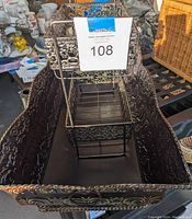 Photo of decorative metal shelf placed inside large ornate metal tray showing intricate metalwork and tiered design.