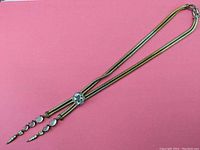 Vintage silver-toned lariat style necklace with moonstone gemstones displayed on pink background