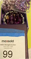 Box with assorted purple vintage costume jewelry pieces including wrapped beads and a purple stretch bracelet.