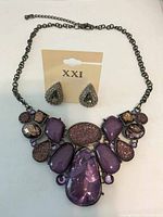 Purple costume jewelry necklace laid flat with matching earrings on an XX1 card