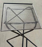 Top view of the small square metal mesh patio table showing the mesh surface and frame structure.
