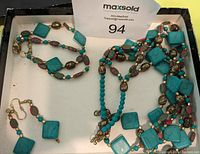 Top view of the jewelry set in a box showing necklace, bracelet, and earrings with turquoise and gold-tone beads.