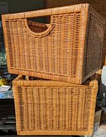 Photo showing two stacked rectangular wicker storage baskets. The baskets are natural wicker color with woven weave and flat rims.