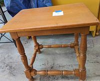 Side view of the wooden side table showing turned legs and stretcher supports