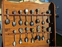 Front view of the wooden spoon rack holding an assortment of souvenir spoons (not included in lot).