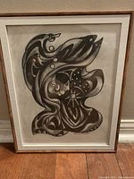 Frontal view of the framed black and white native artwork showing flowing abstract shapes and figure.