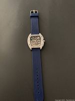 Full view of the wristwatch showing the blue rubber strap and tonneau-shaped stainless steel case.