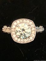 Close-up front view of ring showing central mossanite and surrounding halo in silver setting.