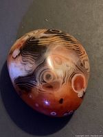 Top view of a polished red agate stone showing distinct banding and translucent finish.