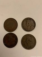 Four copper coins laid out on a flat surface, showing front sides with monarch portraits and inscriptions.