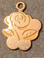 Close-up photo of 10K gold rose pendant charm showing the flower design and attachment loop