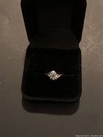 Ring displayed in black velvet ring box, showing front view of the gemstone and band.